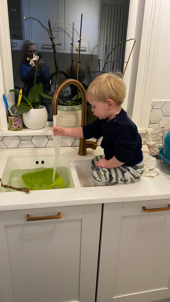 Child playing in kitchen sink